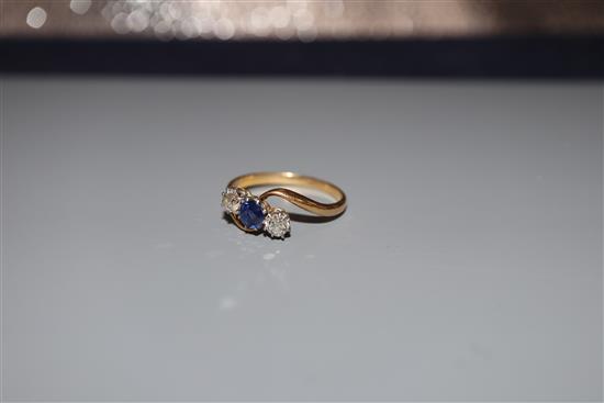 A yellow metal, sapphire and diamond three stone crossover ring, size O, gross weight 2.3 grams.